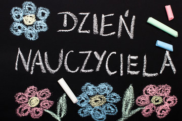 Szkolna tablica z napisem Dzień Nauczyciela, oraz narysowane kredą kolorowe kwiaty. 
