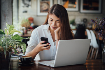 Asian business girl working and drinking coffee in cafe with laptop