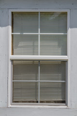Cheap plastic window blinds behind a double-hung window with a white wooden frame