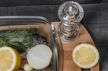 raw trout, fish with spices, herbs and lemon in a baking dish top view