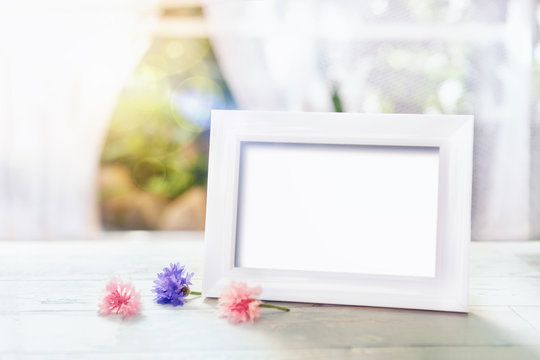 Empty white frame mockup and flowers