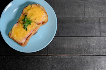 Sandwich with meat, cheese and greens on a blue plate