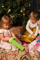 Happy kids with presents next to Christmas tree