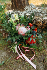 A rustic wedding bouquet with pink ribbons near the log