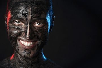 fun woman with black dirty smeared make up on black background