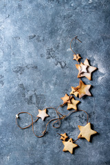 Homemade shortbread star shape sugar cookies different size with sugar powder on thread over blue texture surface. Christmas treat background. Top view with space