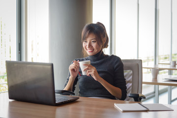 Businesswoman working while holding coffee cup in the office