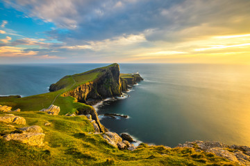Beautiful golden light at sunset at Neist Point Lighthouse on the Isle of Skye, Scotland. - obrazy, fototapety, plakaty