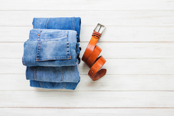 Men's casual outfits with jeans clothing and belt on white wooden board background, fashion and beauty concept, flat lay 