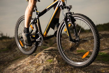 Fototapeta na wymiar Close up Photo of Cyclist Riding Bike Down the Rock. Extreme Sport and Enduro Biking Concept.