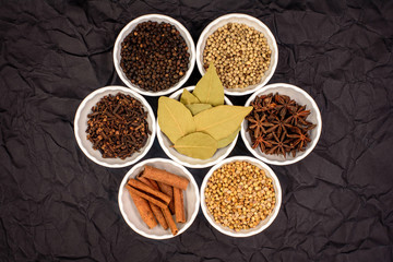 herbs and spices in a cup and dark background