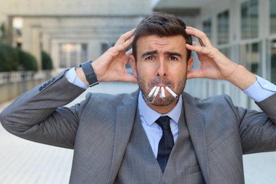 Stressed out businessman smoking four cigarettes at the same time