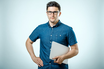 Fototapeta premium Confident young handsome man in shirt holding laptop