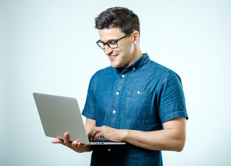 Confident young handsome man in shirt holding laptop