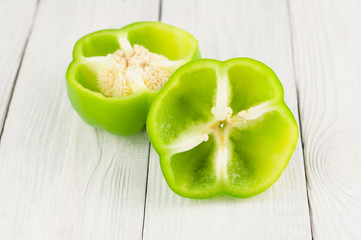 Two halves of green fresh raw pepper on old rural white wooden planks