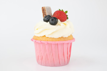 Pink cupcake with white whipped cream decorated with strawberry, blueberry, granola bar on white background. Picture for a menu or a confectionery catalog.