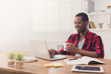 Obraz na płótnie Canvas Happy black businessman in casual office, work with laptop