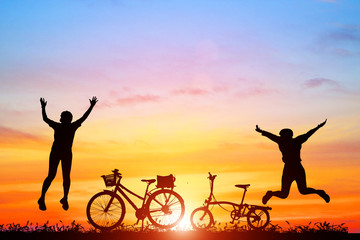 Silhouette of  girl jumping  with a bicycle on sunset sky background
