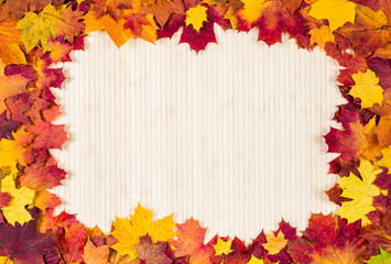Naklejka na ściany i meble Autumn leaves on a wooden background. Frame for inscription.