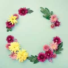 Circle frame of autumn flowers - chrysantemum and asters, on blue background