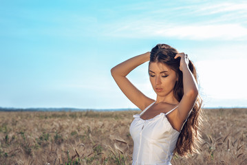 Girl in a white dress field, wheat outdoor recreation, beautiful dress. Woman posing outdoors in long hair.