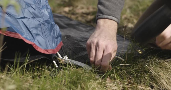 Man and woman setting up camping tent place in  birch woods forest.detail of hammer. Couple people in love autumn outdoor trip in nature. Fall sunny day. 4k slow motion video