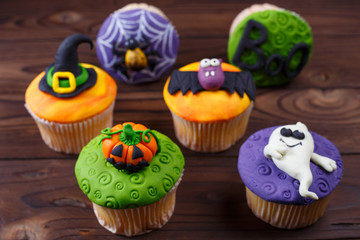 Tasty homemade Halloween cupcakes set with decorations made of confectionery mastic on the table, close up. Halloween treats, sweets concept