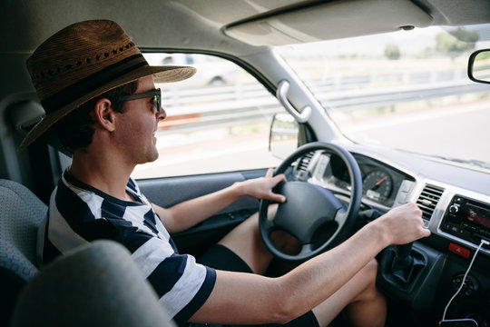 Young man with a straw hat and sunglasses driving a van on a highway