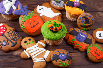 Delicious homemade Halloween treat for dessert,cupcakes and ginger cookies with sweet funny decorations made of confectionery mastic on the table