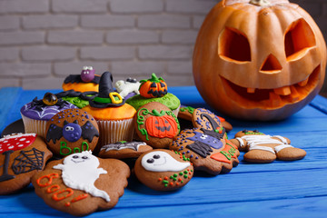 Halloween homemade gingerbread cookies and cupcakes background with carved pumpkin and copy space