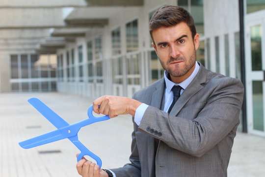 Businessman holding a giant pair of scissors