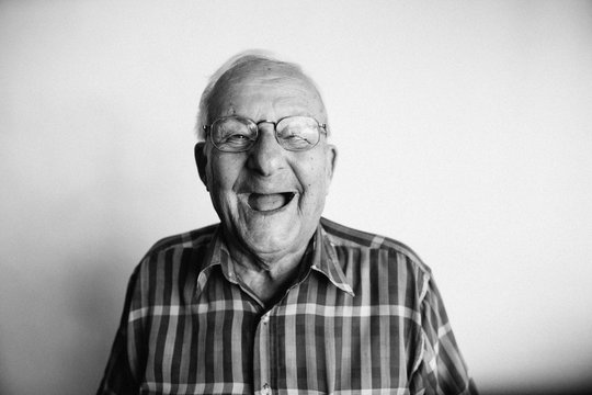 Playful senior man removing dentures and laughing