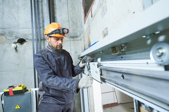 machinist with spanner adjusting lift mechanism in elevator shaft