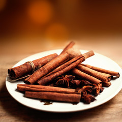 Cinnamon sticks on wooden table with  defocused festive lights on background as Christmas spices