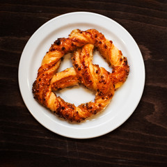 Fresh Bavarian pretzel on dark background with flour. Sweet pretzels with powdered sugar, macro.