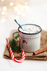 Christmas Card with vintage mug, hot cocoa, marshmallow with xmas holiday decorations and festive symbols with abstract defocused festive lights on background.