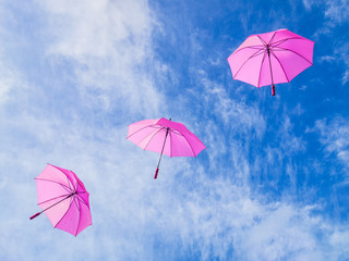 Regenschirme in pink fliegen vor blauem Himmel diagonal - Umbrellas in pink fly before blue sky...