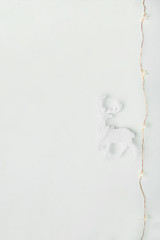 White Reindeer Garland with Glittering Light on Concrete Background. Christmas Greeting Card Poster Template. Scandinavian Style. Minimalist. Copy Space