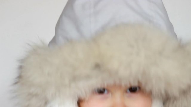 A funny happy child dressed in warm fur clothes looks at the camera, laughs and smiles. Close-up portrait. The concept of winter, frost and snow, cold weather, Cool temperature and Christmas.