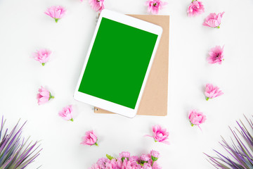 Office desk tablet work space table top view overhead above show tablet on notebook brown around flowers pink so beautiful green screen