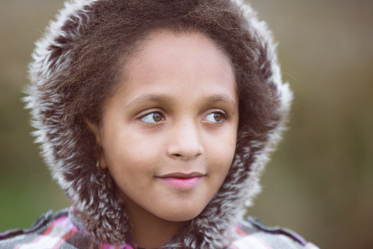 Closeup portrait of a beautiful young girl with shaggy winter hoody smiling sweetly