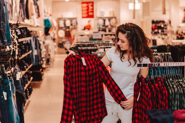 Brunette female customer selecting basic garments at the store.