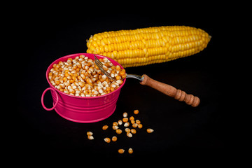 yellow fresh corn seed in bucket with fork on black background