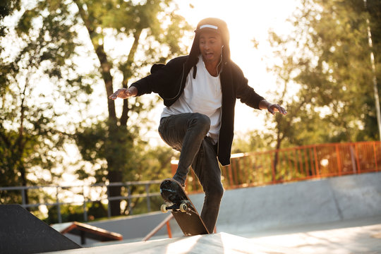 Afro american guy jumping with his skate - Powered by Adobe