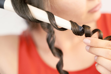 Hairstylist curling hair client in hairdressing salon