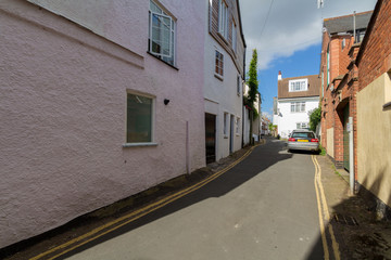 Fototapeta na wymiar Very narrow street in Topsham. A car is parked on the road. Devon. UK