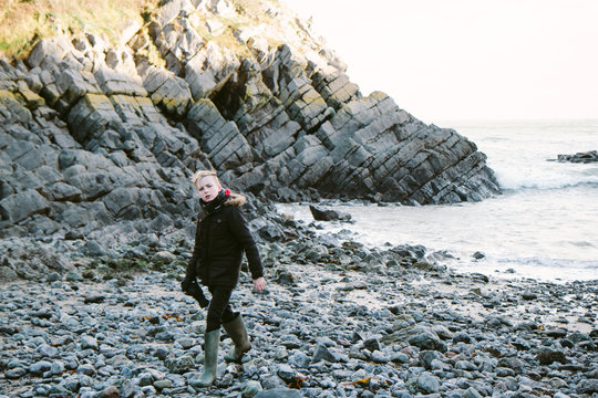Teenage boy walking on a rocky foreshore