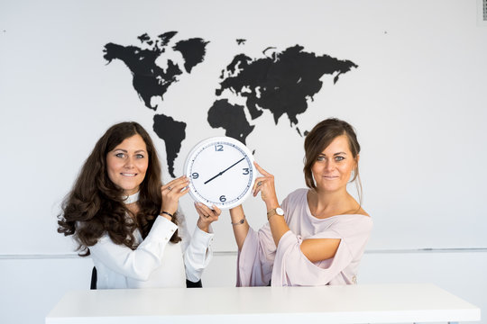Two young girls twins with clock on the background of the world map - Powered by Adobe