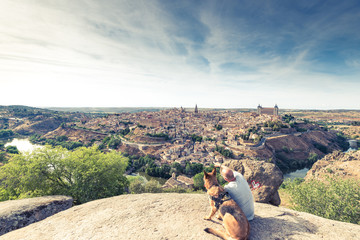 TRaveller man and dog watching Toledo cityscape from hill