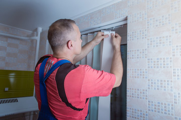 man is installing window blinds